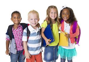 a group of children smiles in front of a white backdrop with school backpacks